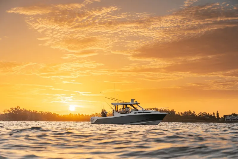 Slide: The Image of Boston Whaler 325CQ at sunset on calm water, equipped for fishing. - 16