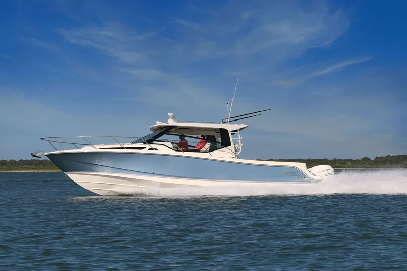 Slide: The Image of 2027 Boston Whaler 325CQ on the water, featuring a blue hull and two people on board. - 36