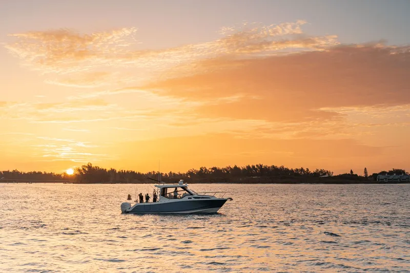 Slide: The Image of A Boston Whaler 325CQ boat cruises on calm waters at sunset. - 18