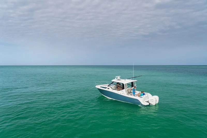 Slide: The Image of A 2027 Boston Whaler 325CQ cruising on calm, turquoise waters under a cloudy sky. - 30