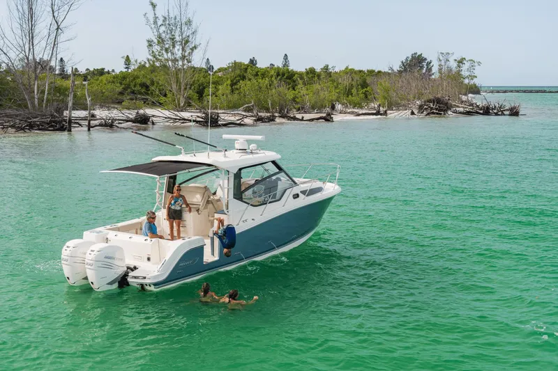 Slide: The Image of A 2027 Boston Whaler 325CQ on turquoise water with people swimming and relaxing. - 34