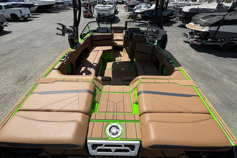 Slide: The Image of 2023 Supra SL 400 boat interior with tan seating and green accents, docked among other boats. - 12