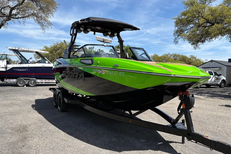 Slide: The Image of 2023 Supra SL 400 boat in vibrant green on a trailer, parked outdoors. - 4
