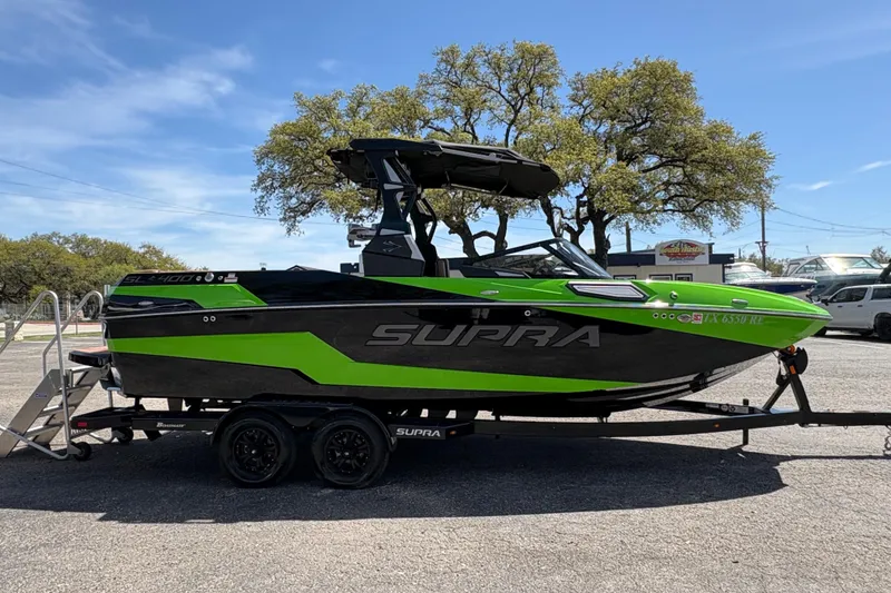 Slide: The Image of 2023 Supra SL 400 boat in vibrant green and black, parked on a trailer. - 6
