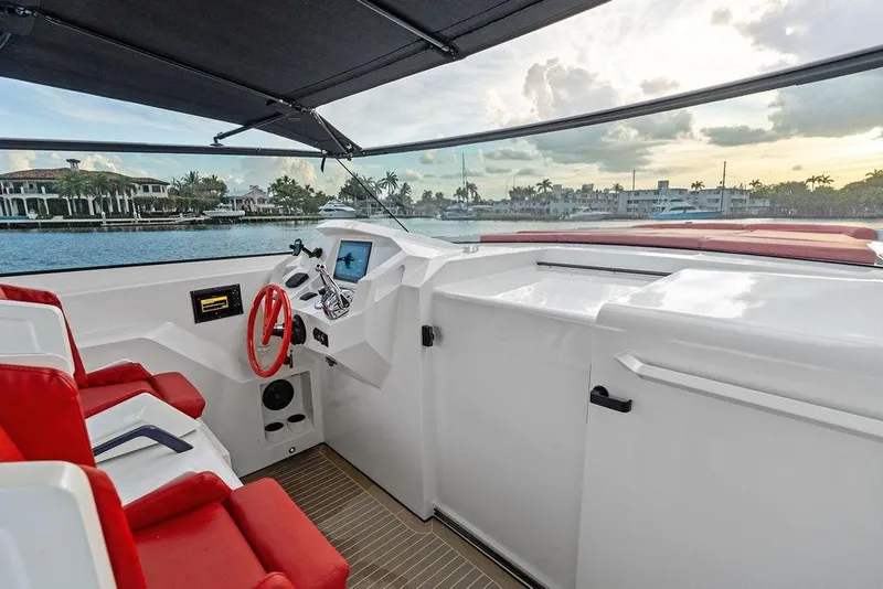Slide: The Image of 2016 Vanquish Yachts VQ48 helm with red seating, overlooking waterfront homes. - 13