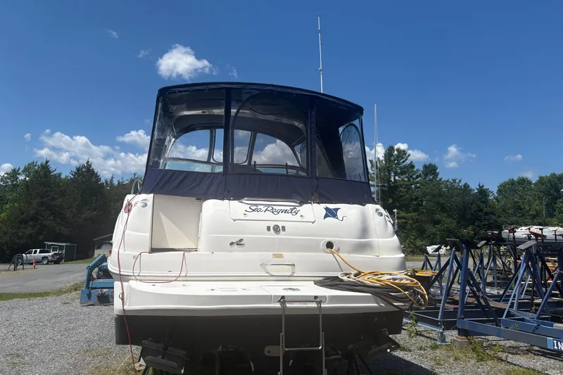 The Image of 2000 Sea Ray 340 Sundancer boat on land, blue canopy, clear sky background. - 0