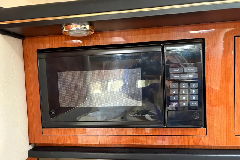 Slide: The Image of Built-in microwave in 2000 Sea Ray 340 Sundancer yacht, featuring wood paneling and digital controls. - 18