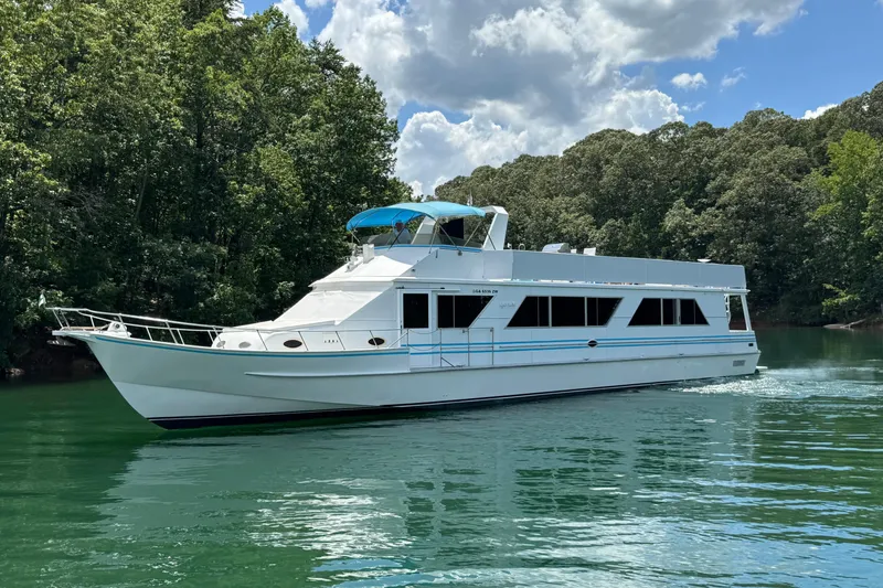 The Image of 1997 Lazy Days 16x85 houseboat cruising on a serene lake with lush green surroundings. - 0