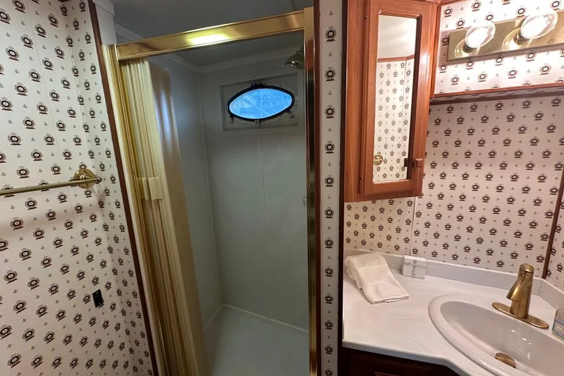 Slide: The Image of Luxurious 1997 Lazy Days 16x85 bathroom with shower, vanity, and nautical-themed wallpaper. - 10