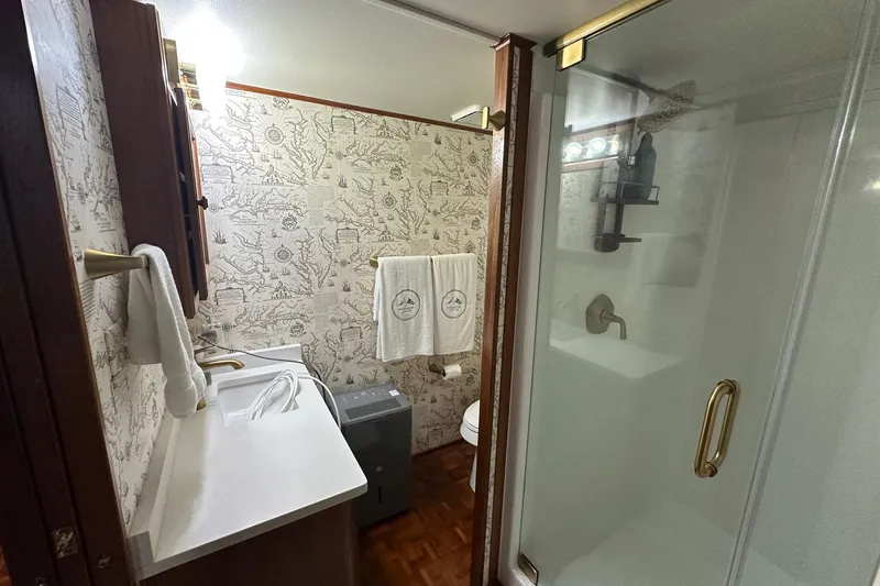 Slide: The Image of Bathroom in 1997 Lazy Days 16x85 houseboat with shower, sink, and nautical-themed wallpaper. - 7
