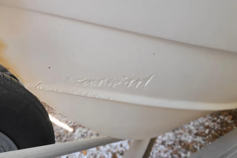 Slide: The Image of 1983 Mako 20 Center Console boat hull with visible scratches near trailer wheel. - 21