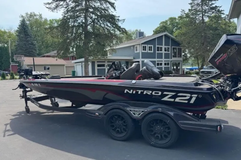Slide: The Image of 2022 Nitro Z21 XL boat parked on driveway with trees and houses in background. - 8