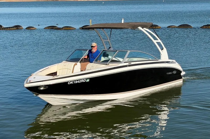 Slide: The Image of 2013 Cobalt 232 boat cruising on a calm lake with a person at the helm. - 3