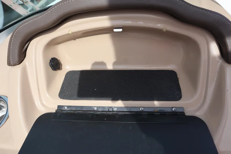 Slide: The Image of 2021 Chaparral 21 SSi boat dashboard with storage compartment and brown trim. - 23