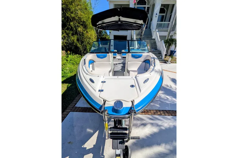 Slide: The Image of 2017 Chaparral Vortex 223 VRX boat with blue and white design, parked on a driveway. - 5