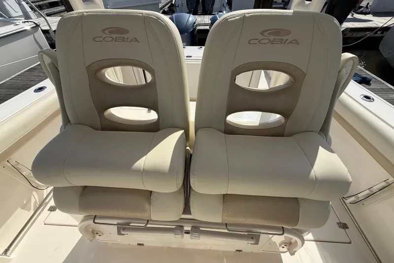 Slide: The Image of 2017 Cobia 296 Center Console boat seats with logo, docked at marina. - 18