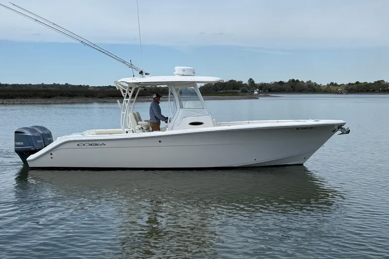 Slide: The Image of 2017 Cobia 296 Center Console boat on calm water with dual Yamaha engines. - 2