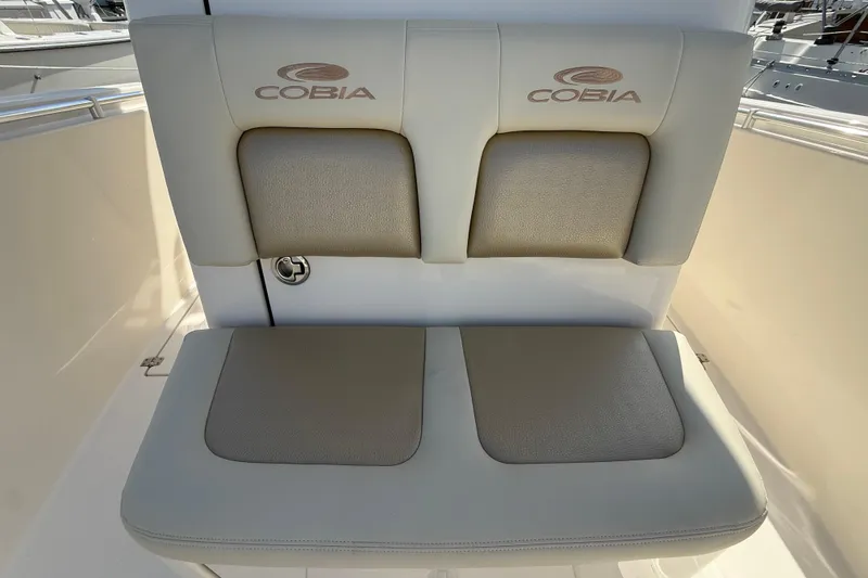 Slide: The Image of Cobia 296 Center Console 2017 boat seating with logo, featuring cushioned backrest and seat. - 26