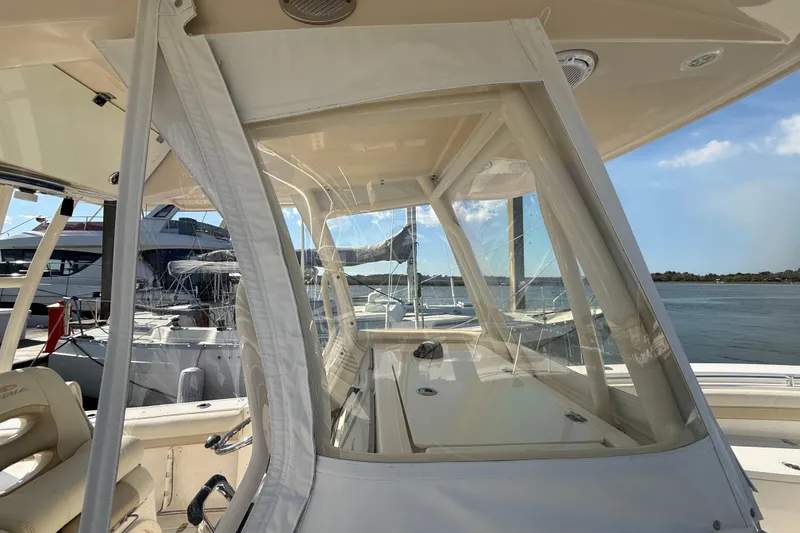 Slide: The Image of 2017 Cobia 296 Center Console boat interior with clear enclosure, docked by the water. - 35
