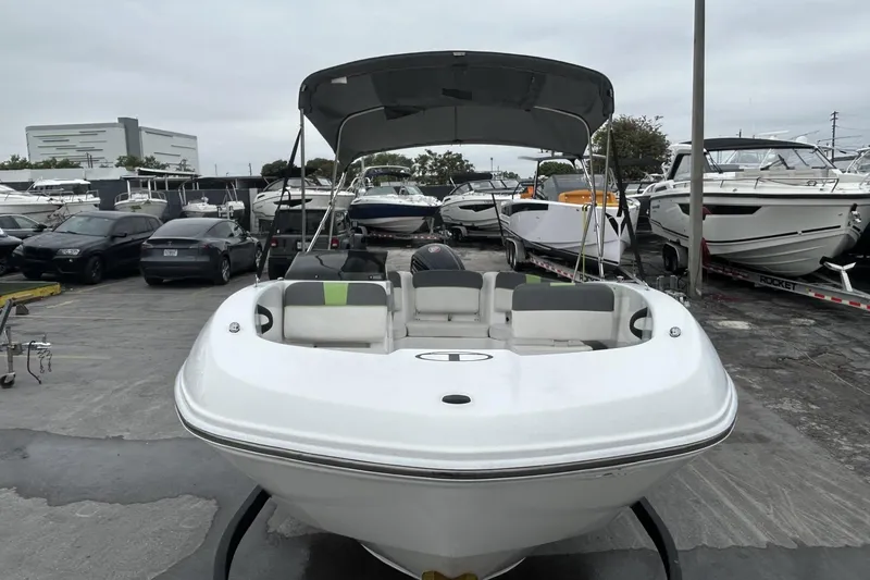 Slide: The Image of 2022 Tahoe T18 boat with canopy in a marina, surrounded by other boats and cars. - 37