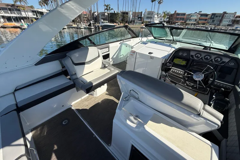 Slide: The Image of 2015 Cruisers Yachts 338 Bow Rider interior with modern dashboard and seating in marina. - 11