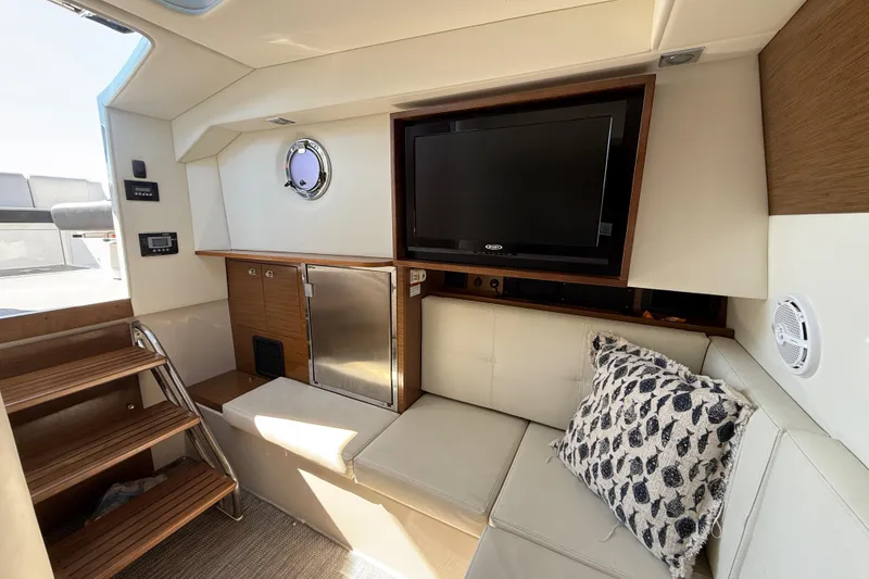 Slide: The Image of 2015 Cruisers Yachts 338 Bow Rider interior with TV, seating, and wooden accents. - 17