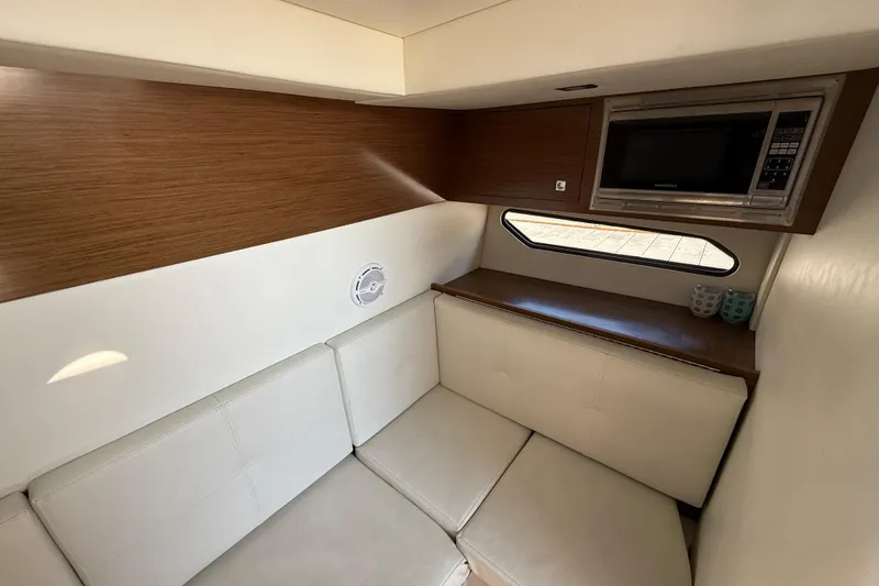 Slide: The Image of 2015 Cruisers Yachts 338 Bow Rider interior with seating, microwave, and window. - 19