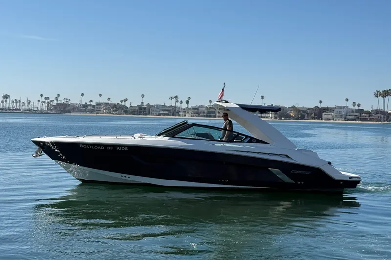 Slide: The Image of 2015 Cruisers Yachts 338 Bow Rider on calm water, coastal background. - 2
