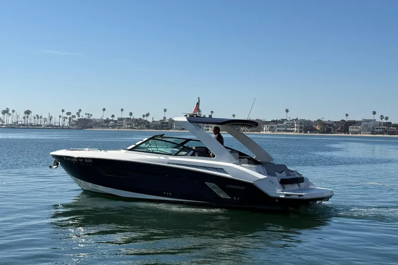 Slide: The Image of 2015 Cruisers Yachts 338 Bow Rider on calm water, coastal backdrop. - 4