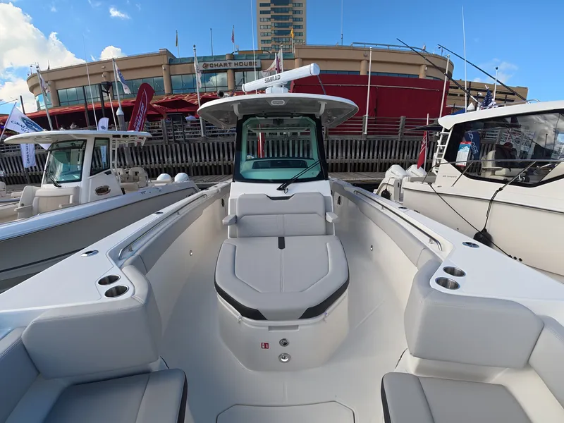 Slide: The Image of A 2027 Boston Whaler 330 Outrage docked at a marina. It features a modern design with comfortable seating. - 19