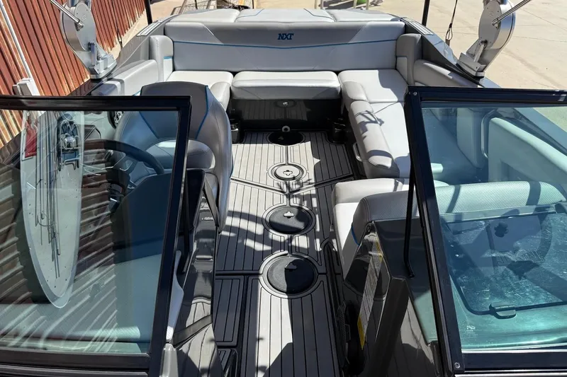 Slide: The Image of 2018 MasterCraft NXT22 boat interior with gray seating and open cockpit view. - 18