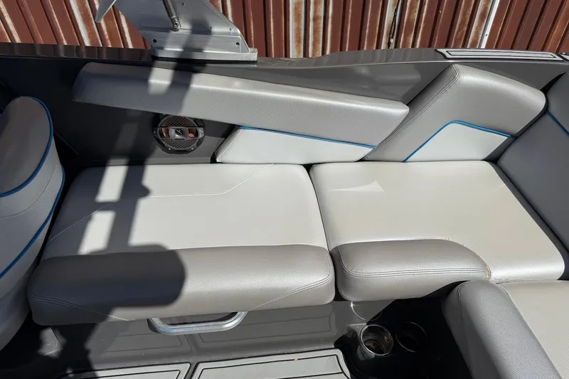 Slide: The Image of 2018 MasterCraft NXT22 boat interior with gray and white seating, blue accents, and cup holders. - 20