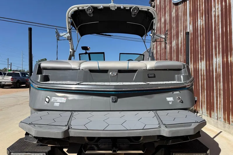Slide: The Image of 2018 MasterCraft NXT22 boat, rear view, parked outdoors near a metal building. - 3