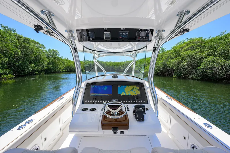 Slide: The Image of Cockpit view of 2025 Valhalla V-37 boat navigating a lush, green waterway. - 13
