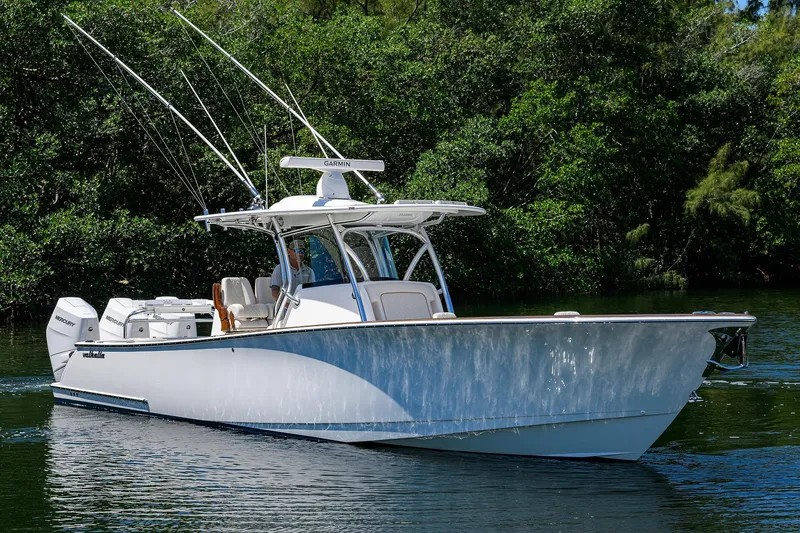 Slide: The Image of 2025 Valhalla V-37 boat cruising on a calm river with lush greenery. - 2