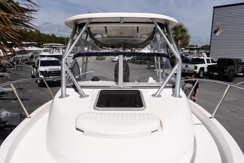 Slide: The Image of 2005 Boston Whaler 235 Conquest boat at a marina with parked vehicles. - 15