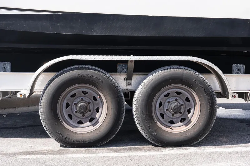 Slide: The Image of Trailer wheels for 2005 Boston Whaler 235 Conquest boat, parked on pavement. - 19