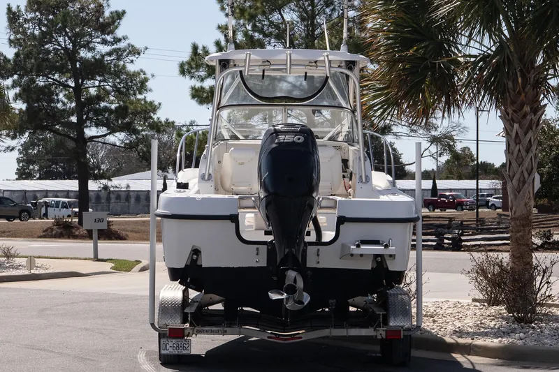 Slide: The Image of 2005 Boston Whaler 235 Conquest boat on trailer, parked near palm trees. - 6