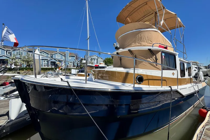 Slide: The Image of 2019 Ranger Tugs R-31 CB boat docked, featuring a blue hull and tan canopy. - 18