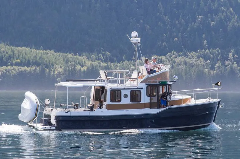 Slide: The Image of Manufacturer Provided Image: 2019 Ranger Tugs R-31 CB cruising on a serene lake with forested mountains in the background. - 2
