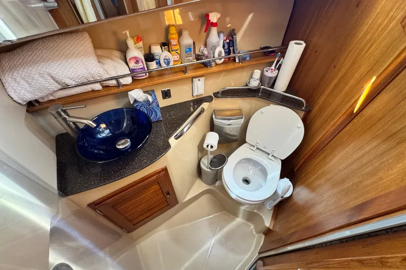 Slide: The Image of 2019 Ranger Tugs R-31 CB bathroom with blue sink, toilet, and wooden cabinetry. - 27