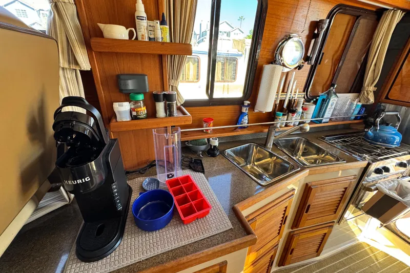 Slide: The Image of Cozy 2019 Ranger Tugs R-31 CB galley with coffee maker, dual sinks, and wooden cabinetry. - 31