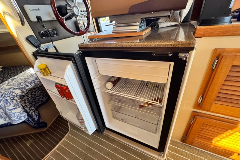 Slide: The Image of 2019 Ranger Tugs R-31 CB interior with open mini fridge and wooden cabinetry. - 32