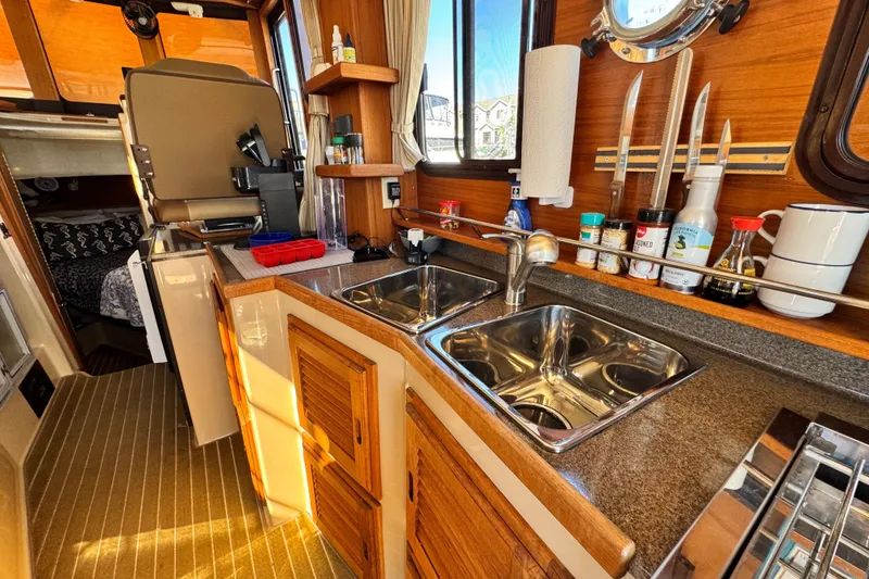 Slide: The Image of 2019 Ranger Tugs R-31 CB boat kitchen with dual sinks and wooden cabinetry. - 36