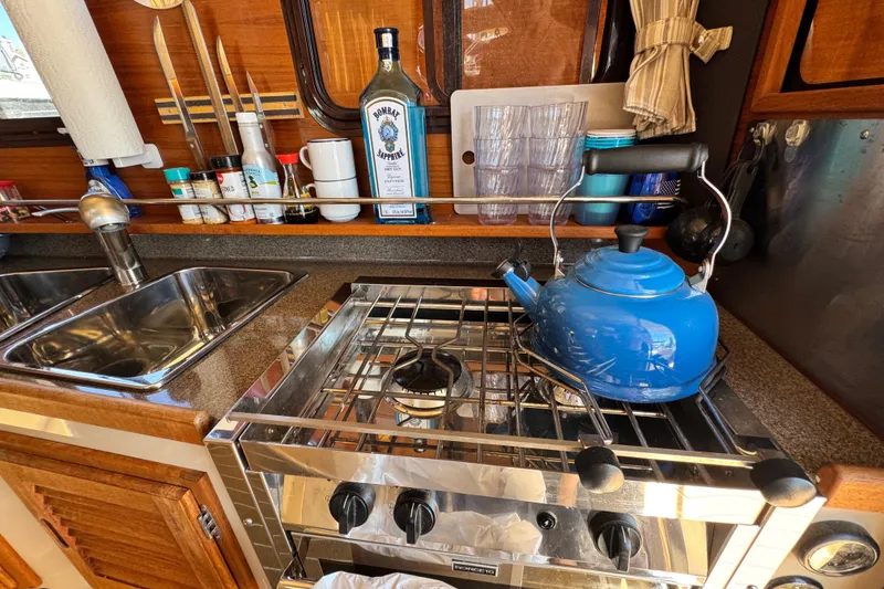 Slide: The Image of Compact kitchen in 2019 Ranger Tugs R-31 CB with blue kettle and stainless steel stove. - 37