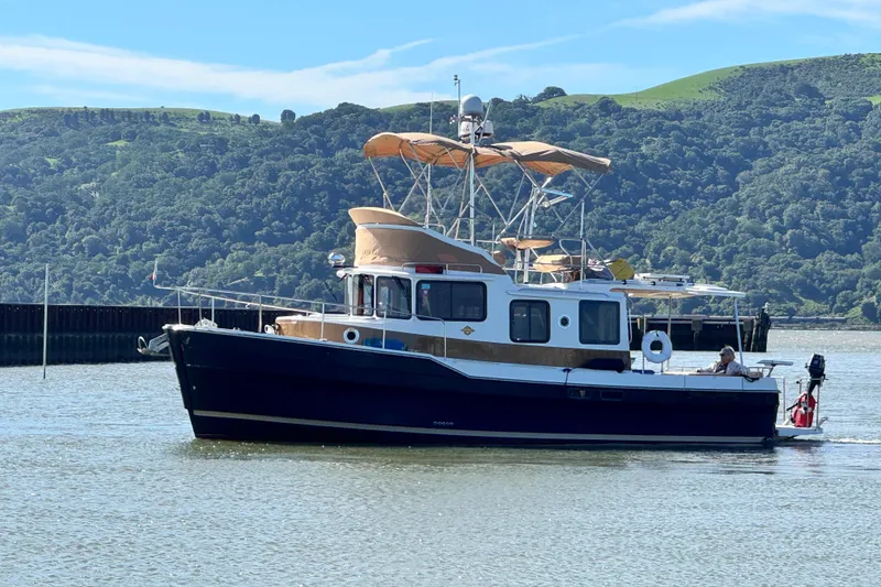 Slide: The Image of 2019 Ranger Tugs R-31 CB cruising on a scenic lake with lush green hills. - 41