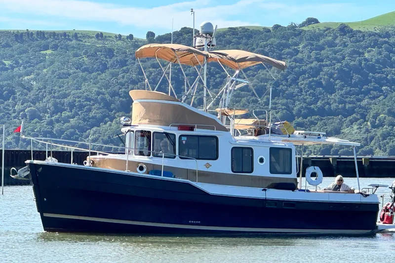 Slide: The Image of 2019 Ranger Tugs R-31 CB boat on water with scenic green hills in background. - 42
