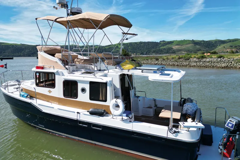 Slide: The Image of 2019 Ranger Tugs R-31 CB boat docked on a scenic river with hills in the background. - 43