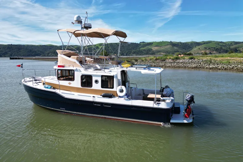 Slide: The Image of 2019 Ranger Tugs R-31 CB cruising on a scenic river with lush green hills. - 44