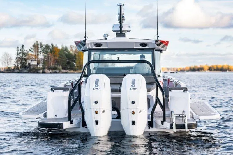 Slide: The Image of 2026 Axopar 38 Cross Cabin boat with dual outboard engines on a scenic lake. - 7